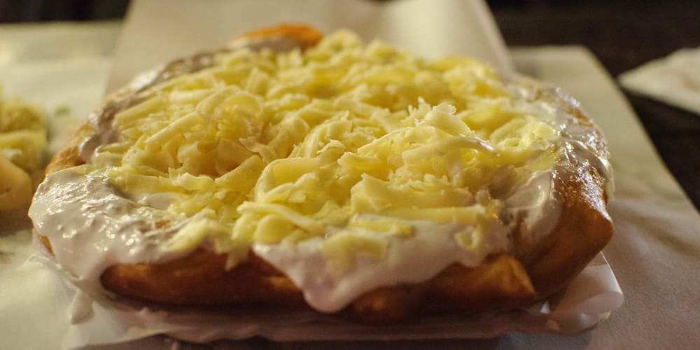 Pieza de lángos con cobertura de crema y queso.